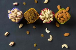 hälsosam blandning torra frukter och nötter på mörk bakgrund. mandlar, pistasch, cashewnötter, russin foto