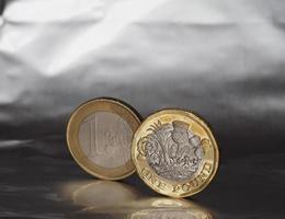 1 pund och 1 euro mynt över metall bakgrund foto