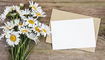 tomt vitt gratulationskort och kuvert med kamomillblommor foto