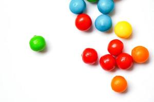 färgade godis - färgglada små choklad godis på vit bakgrund, ovanifrån foto