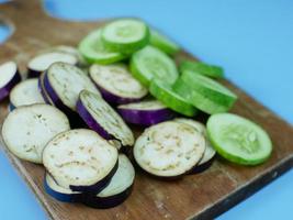 skivad aubergine och gurka på en skärbräda av trä. hälsosamt grönsakskoncept för diet foto