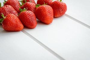 läckra färska jordgubbar på en vit trä bakgrund foto