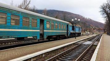 ukraina, yaremche - 20 november 2019. tåg på stationen på en bakgrund av berg. unika järnvägsvagnar på perrongen i staden yaremche. gammalt diesel persontåg. järnvägsstation. foto