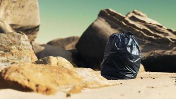 svart plastsoppåse full av skräp på stranden foto