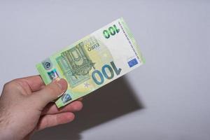 hundra euro sedel hålls upp i en hand inflationen på marknaden med grått foto