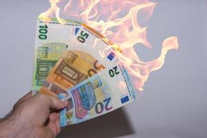 hand som håller tre brinnande eurosedlar inflationen i finansen foto