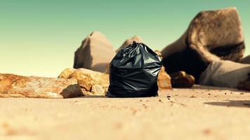 svart plastsoppåse full av skräp på stranden foto