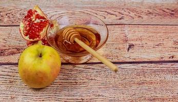 rosh hashanah jewesh holiday torah bok, honung, äpple och granatäpple över träbord. traditionella symboler. foto
