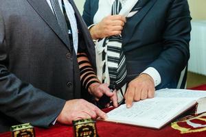 hand av pojken som läser den judiska toran vid bar mitzva foto