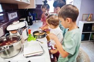 barn som lagar mat i köket, glada barnstunder. de förbereder cheesecake. foto