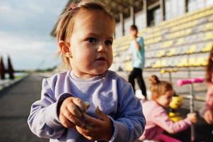 närbild liten flicka i lila sport kostym. sportfamiljen tillbringar fritid utomhus med skotrar och skridskor. foto