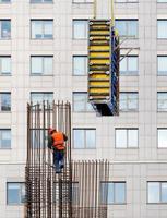 16.02.2021. Kiev. ukraina. en byggare som bär en ljust orange väst och en skyddshjälm installerar formen på en stålram för efterföljande gjutning av betong. foto