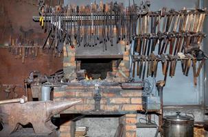 metallstäd i en smedsbutik och olika verktyg i oskärpa. foto