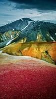 färgglada regnbågs vulkaniska landmannalaugarberg vid den berömda vandringsleden Laugavegur, med dramatisk himmelsvy och snö på Island foto