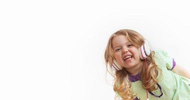 glad rolig liten flicka i hörlurar på vit bakgrund. musik eller underhållning online. banner med kopia utrymme foto
