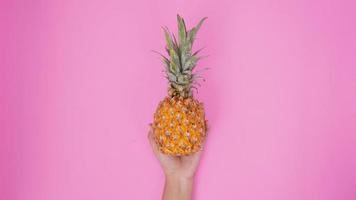 en ananas med en hand isolerad på en rosa bakgrund foto