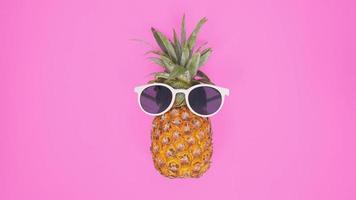 ananas med glasögon isolerad på en rosa bakgrund foto