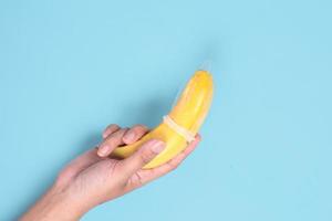 pedagogiskt sex med banan i handen isolerad på blå bakgrund foto