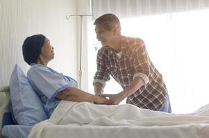 senior man besöker cancerpatient kvinna som bär huvudduk på sjukhus, hälsovård och medicinsk koncept foto