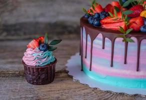hemgjorda cupcakes med rosa och turkos grädde, dekorerade med jordgubbar och blåbär foto