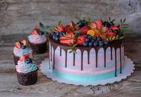 hemgjorda cupcakes med rosa och turkos grädde, dekorerade med jordgubbar och blåbär foto