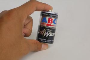 hand som håller ett svart abc-märkebatteri foto