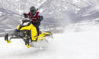 man flyger på en snöskoter på en bakgrund berg foto