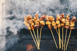 get satay på röd eld grillning av människor. traditionell indonesisk mat gjord på fårkött. foto