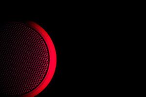 musikalisk högtalare upplyst med rött ljus på en svart bakgrund. foto