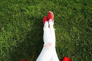 kvinnliga ben i sneakers på en bakgrund av grönt gräs foto