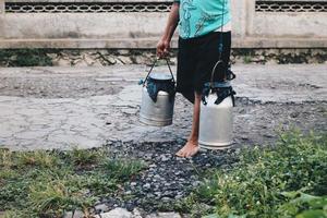 traditionell mejeri arbetare eller mjölk man i boyolali, Indonesien ta med metall glänsande mjölkbehållare eller vattenkokare traditionell burk från traditionell gård foto