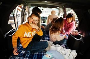 mamma med fyra barn vid fordonsinredning. barn i bagageutrymmet. reser med bil, ligger och har roligt, atmosfär koncept. foto