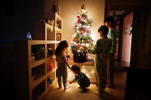 barn tittar på julgran med lysande girlander på kvällen hemma. foto