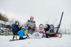 familjens lekar och slädturer på vintern utomhus, barn har roligt, dricker te. foto