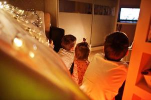 barn i tält tittar på tv på natten hemma. hygge humör. foto