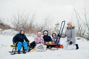 familjens lekar och slädturer på vintern utomhus, mamma och barn har roligt. foto