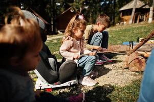 familjens bål i berget. steka korv. mamma med fyra barn camping. höstvandring och lägerväder. uppvärmning och matlagning nära lågan tillsammans. foto