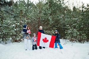 mamma med barn som håller Kanadas flagga på vinterlandskap. foto