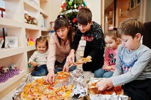 lycklig familj med fyra barn som äter pizza hemma. foto