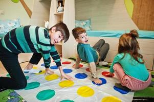 lycklig familj som har roligt tillsammans, fyra barn spelar twister-spel hemma. foto