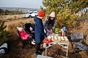 familjen grillar på ett däck i tallskogen. laga mat utomhus. foto