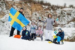 skandinavisk familj med Sveriges flagga i svenska vinterlandskap. foto