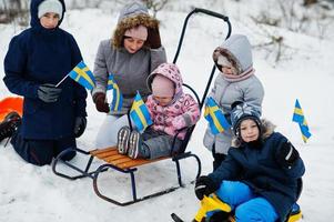 skandinavisk familj med Sveriges flagga i svenska vinterlandskap. foto