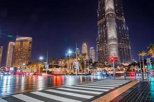 burj khalifa skyskrapa på natten i dubai. upptagen vägskäl med bilar och fotgängare mitt i Dubai. foto