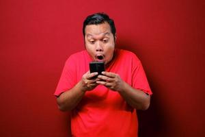 asiatiska män använder smartphones. han tittar på telefonen och ser väldigt förvånad ut. foto