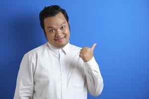 porträtt av asiatisk ung glad kontorsarbetare som ler och pekar på att presentera något på sin sida foto