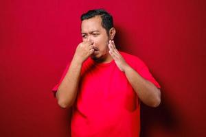 ung asiatisk man stänger näsan för dålig lukt foto