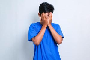 asiatisk man med sorgligt uttryck som täcker ansikte med händer medan han gråter. depression koncept foto