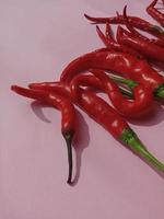 stor röd chili och lockig röd chili. med rosa bakgrund foto