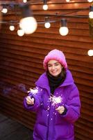kaukasiska flickan har kul på vintern på gatan med tomtebloss i handen foto